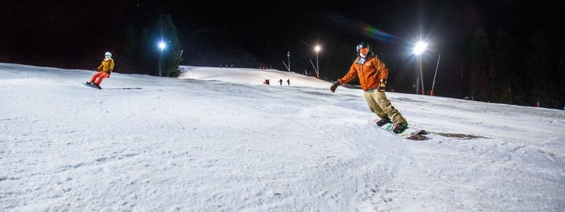 man snowboards down piste whilst night skiing in Morzine