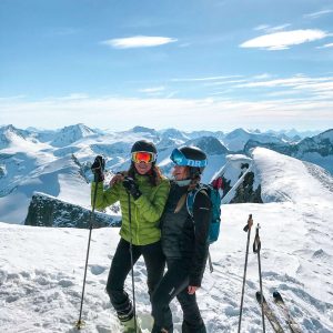 two women pose on snowy mountain